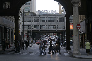 Pedestrian crossing. In the background a bridge with Generali lettering on top seen from Via XX Settembre